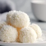 coconut snowball cookies, stacked on a plate
