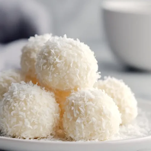 coconut snowball cookies, stacked on a plate