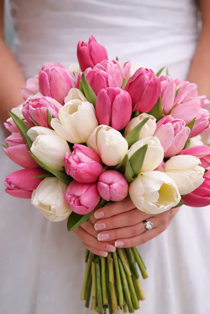 pink and white flowers with stems being held by the bride's hands