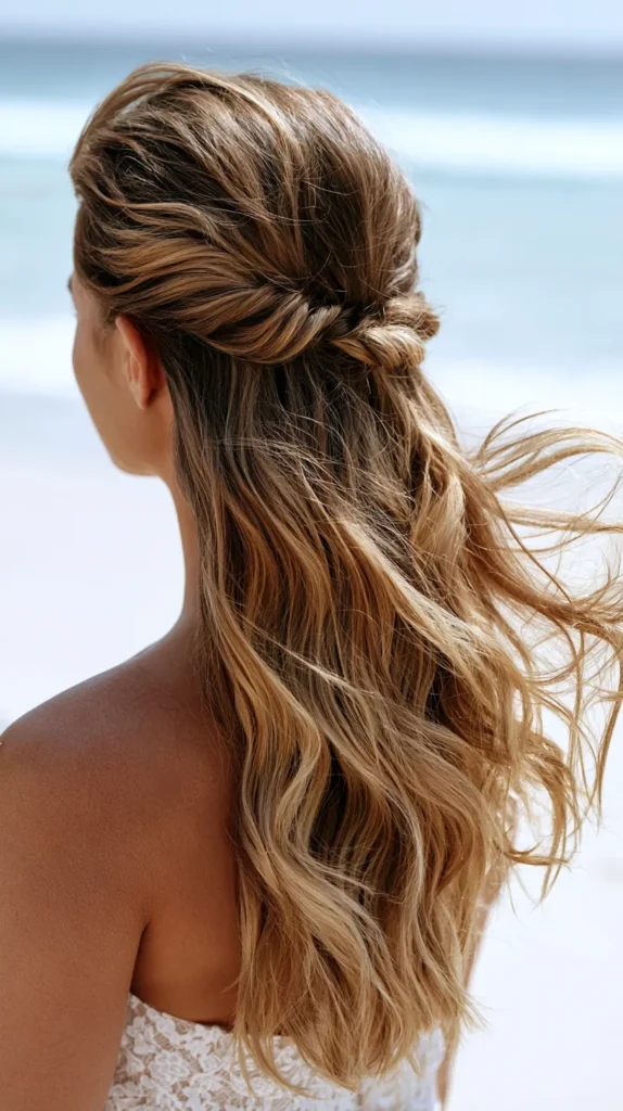 hyper-realistic photo of beach wedding hair in a half-up half-down style, long loose waves, small twisted sections pinned at the back, soft movement from ocean breeze, back view only, no visible face, sandy beach setting, pale blue water, bright natural light, minimal shadows, realistic bridal hair texture, elegant coastal look, no text